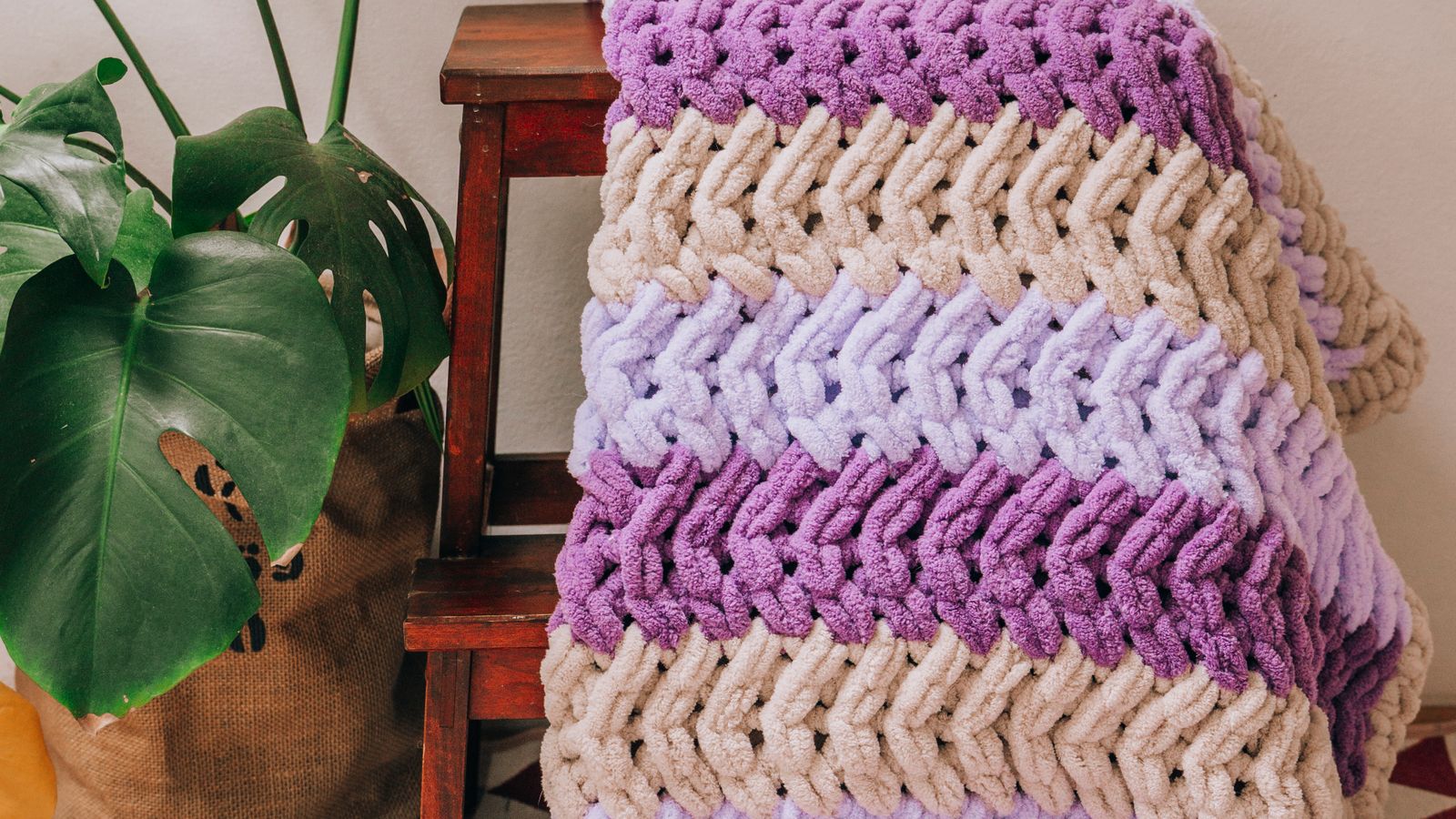 Thick chunky knit blanket folded on a bed in a bright bedroom