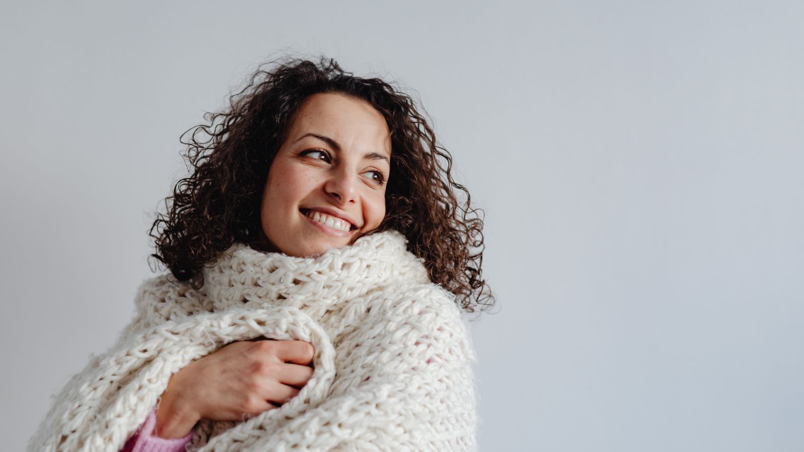 Chunky knit blanket draped over the arm of a living room sofa