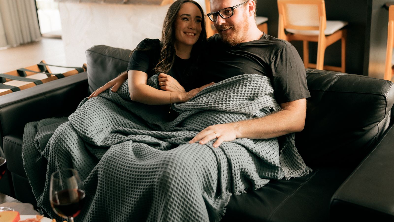 Couple relaxing on a couch under a cozy lightweight blanket at home
