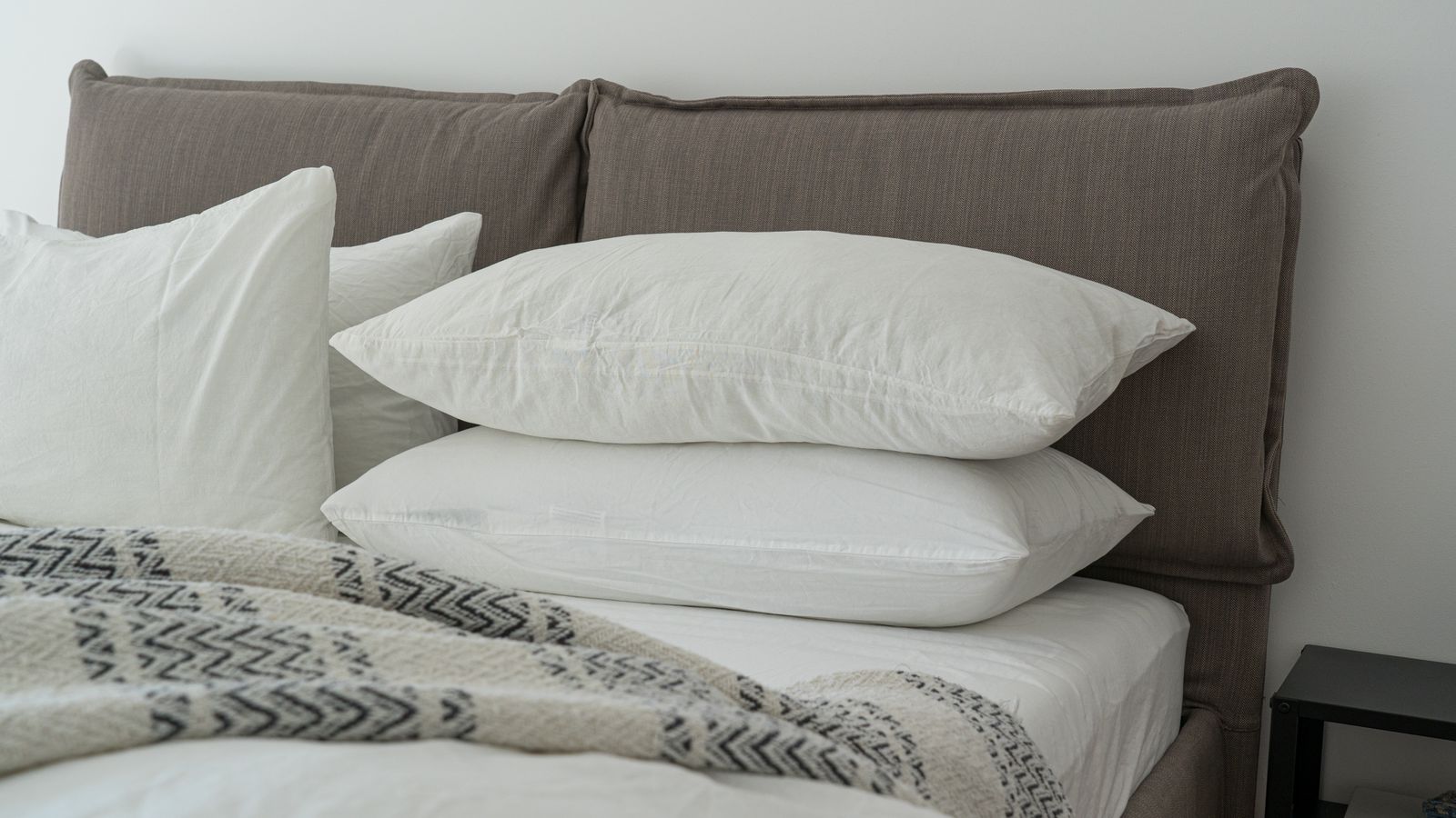 Freshly laundered mattress protector being placed on a bed