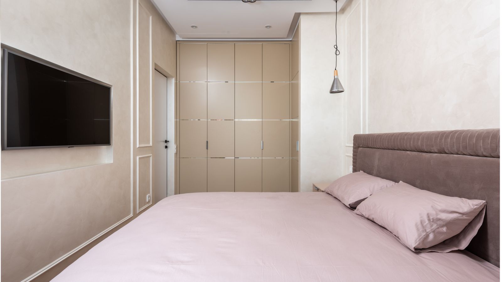 Upholstered wall mounted headboard installed above a neatly made bed