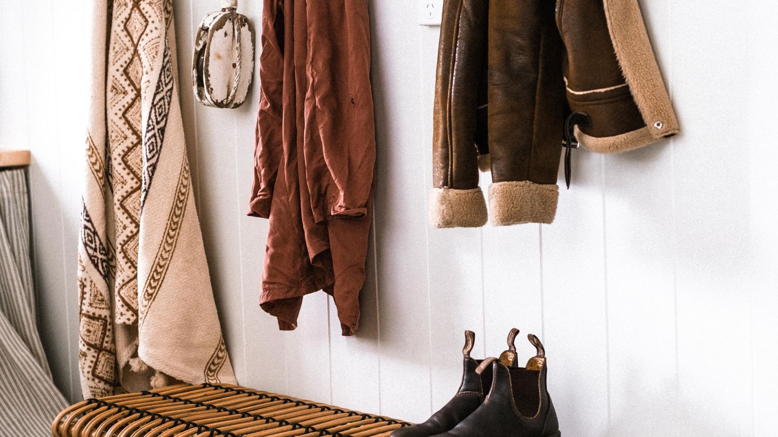 Wooden entryway bench with cushion and storage baskets near a front door