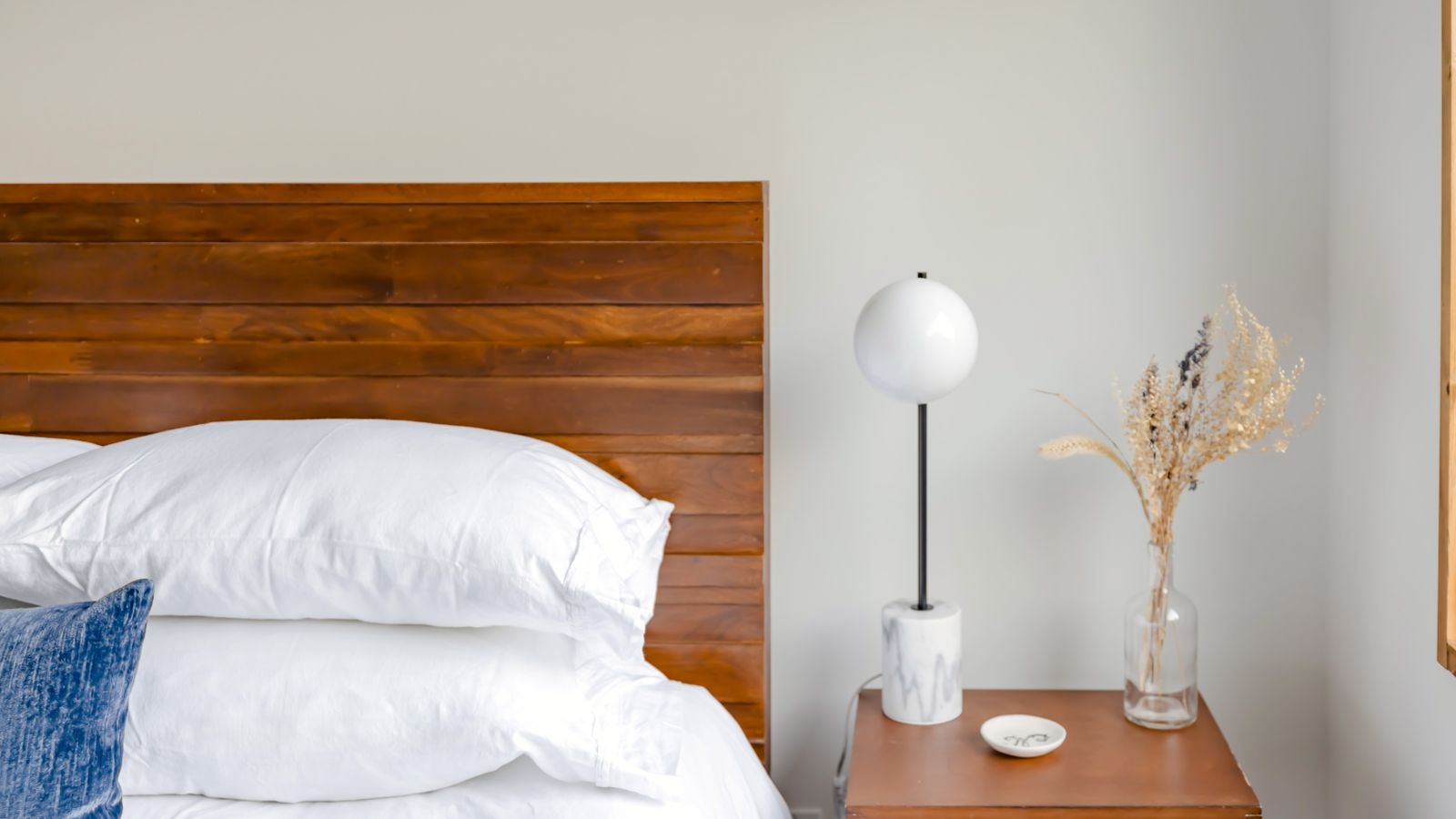 White bed frame with a wooden headboard and matching nightstand in a bright bedroom