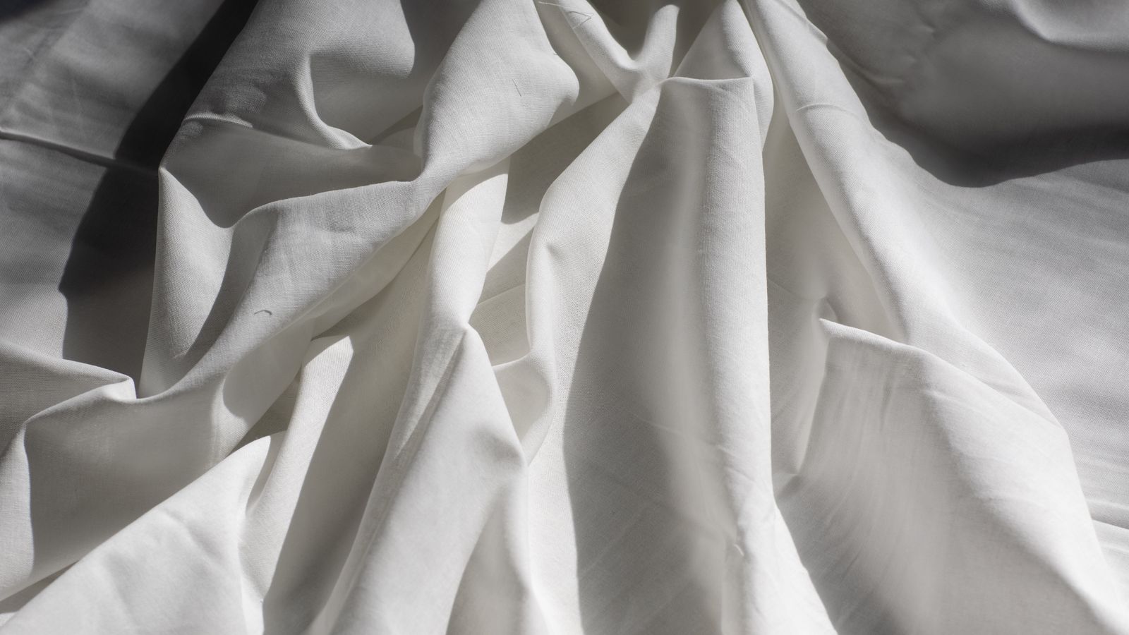 Folded Egyptian cotton sheet set on a bed next to a crib bedding set swatch