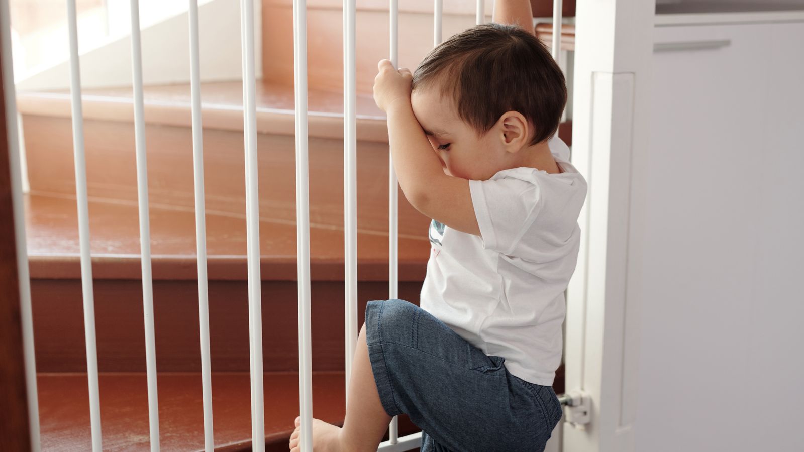 A white baby gate installed at the top of a staircase in a home hallway