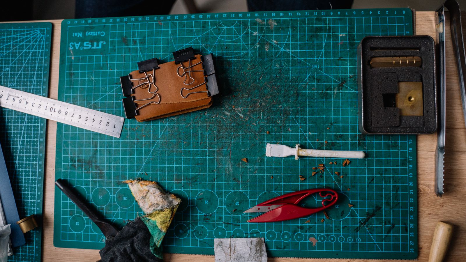Hands wiping down leather repair kit tools with a microfiber cloth