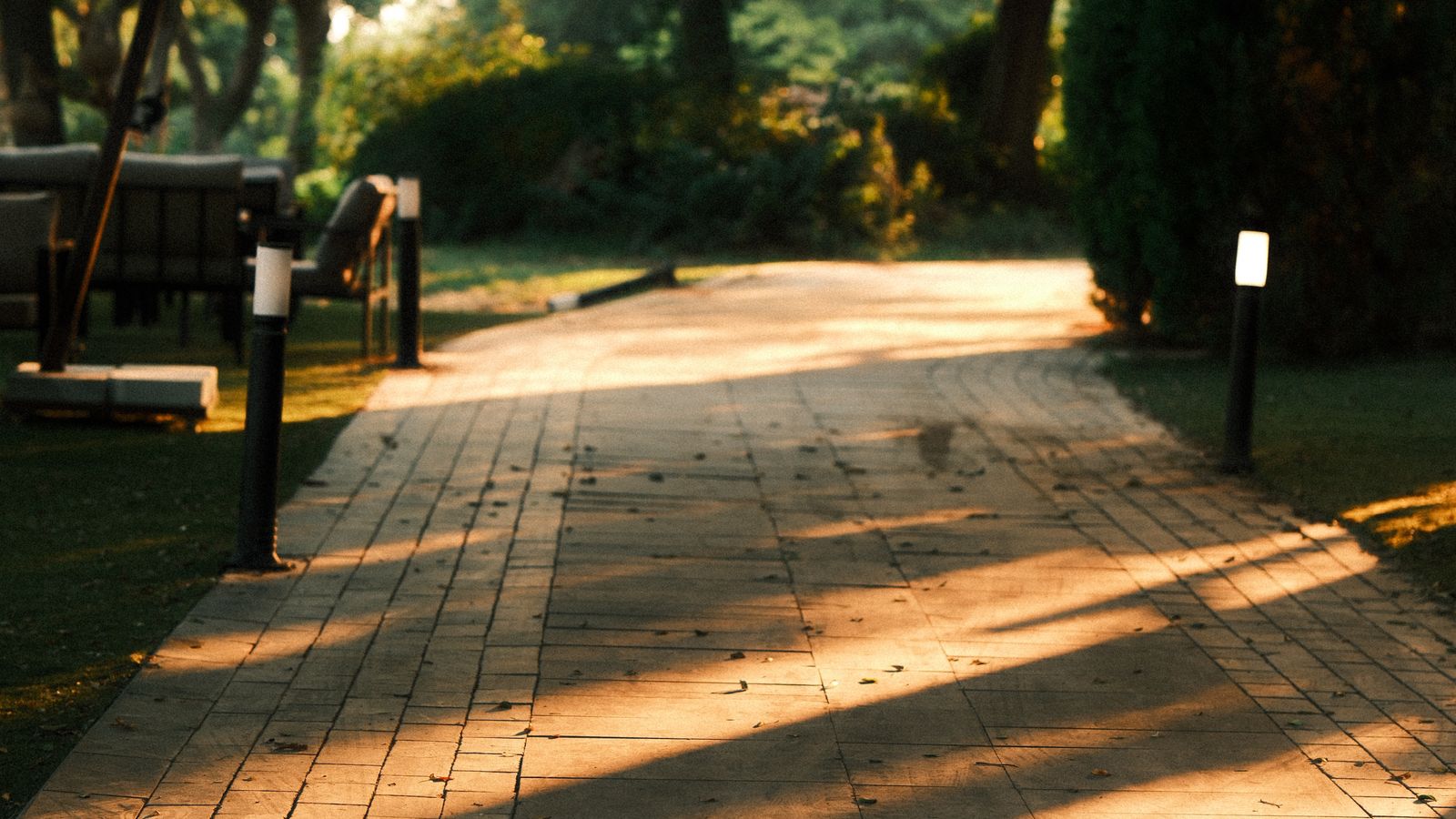 Solar-powered pathway light staked in garden mulch beside a walkway