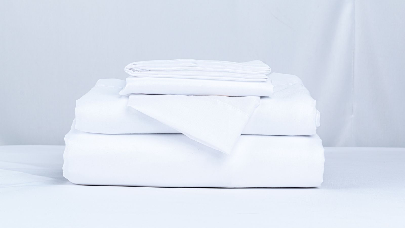 Neatly folded stack of white bed linens ready to be gifted