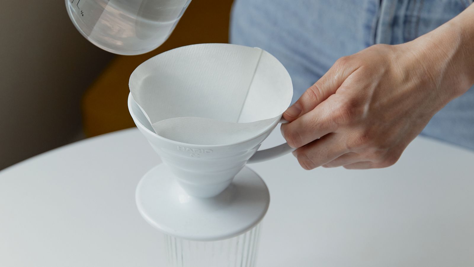 Water filter pitcher on a kitchen counter next to a glass of filtered water
