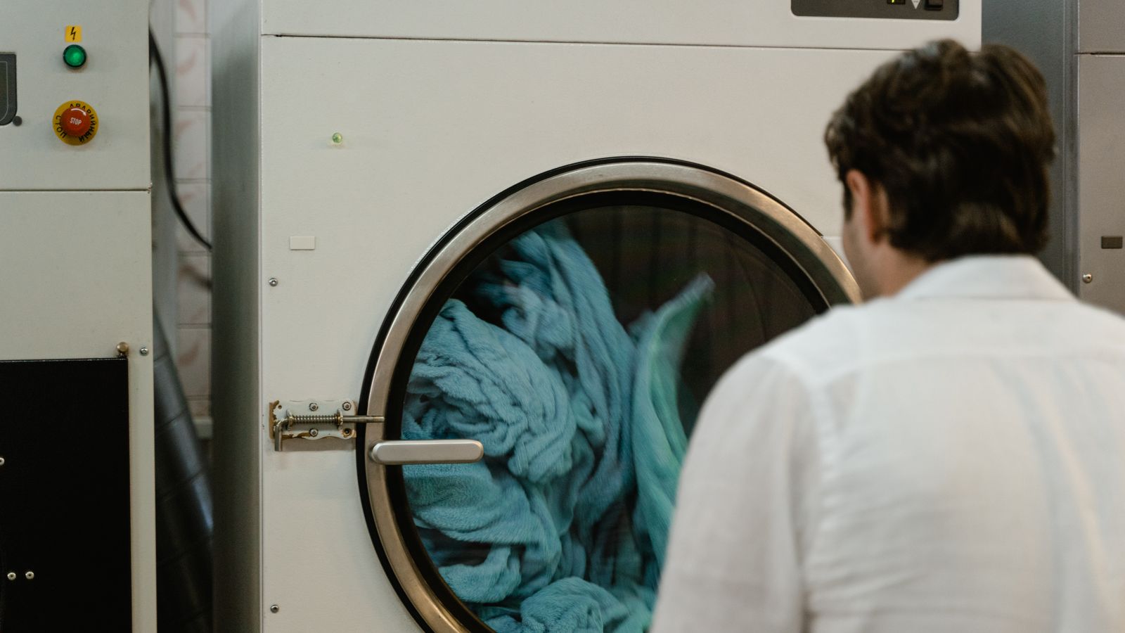 Folded laundry stacked next to a modern washing machine in a bright laundry room