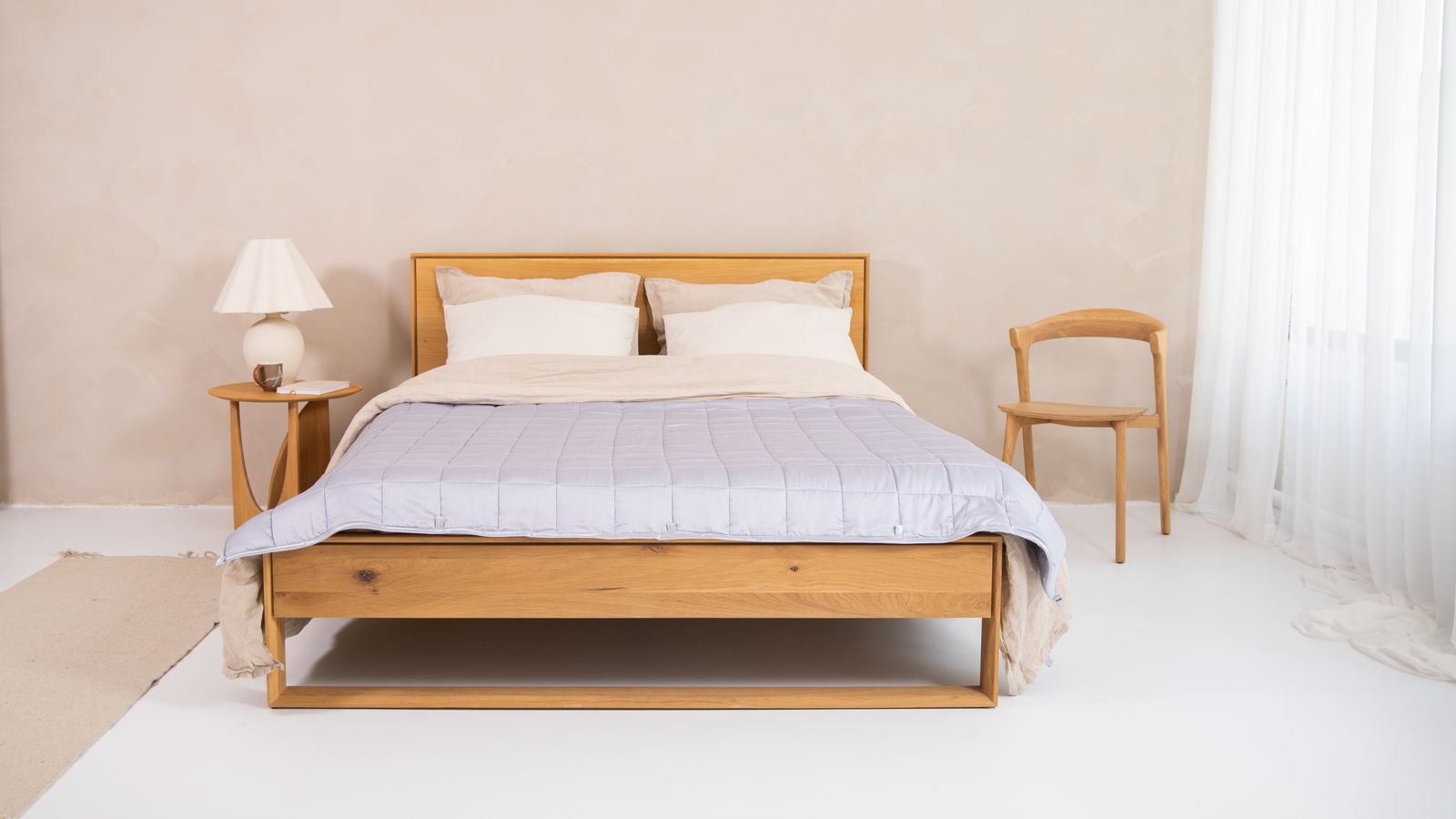Wooden bed frame with slats supporting a mattress and bunkie board setup