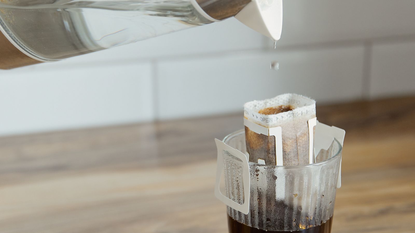 Wiping down the exterior and drip tray of a single serve coffee maker in a kitchen