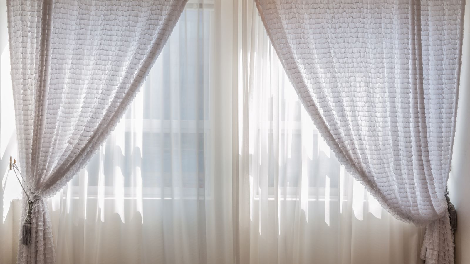 Thick thermal curtain panels hanging beside a bright window