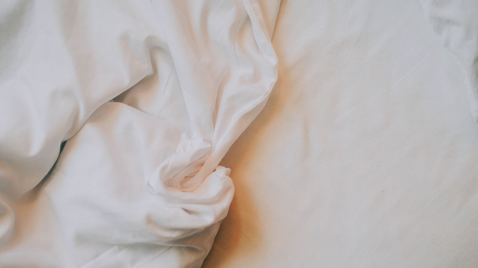 Crinkled white bamboo bed sheets in soft natural light