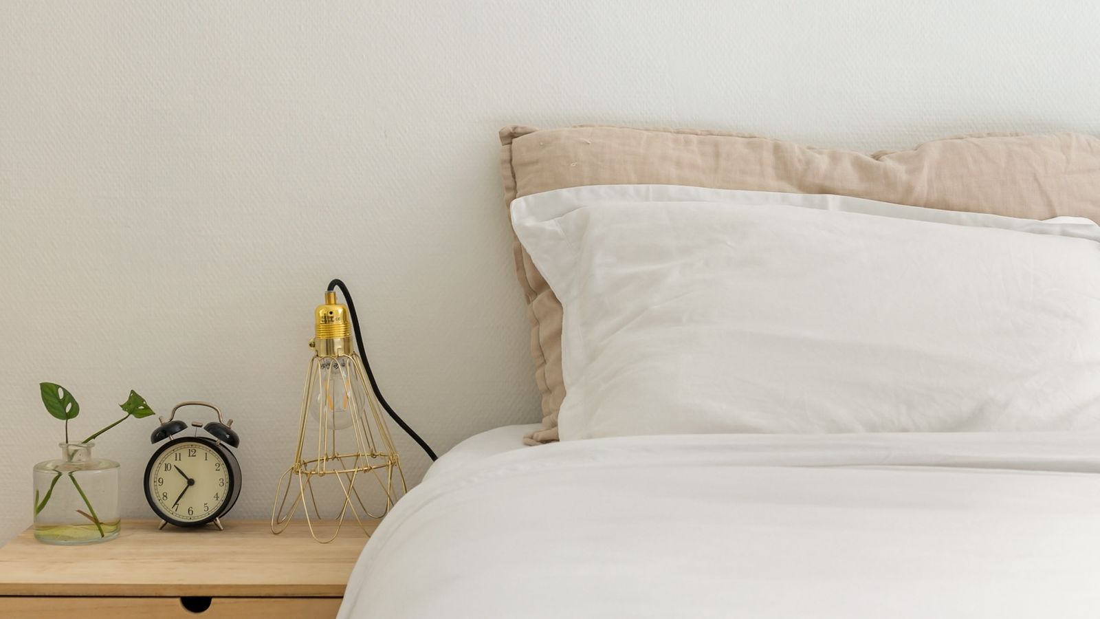 Minimalist bedroom styled with layered neutral bedding and a folded throw blanket