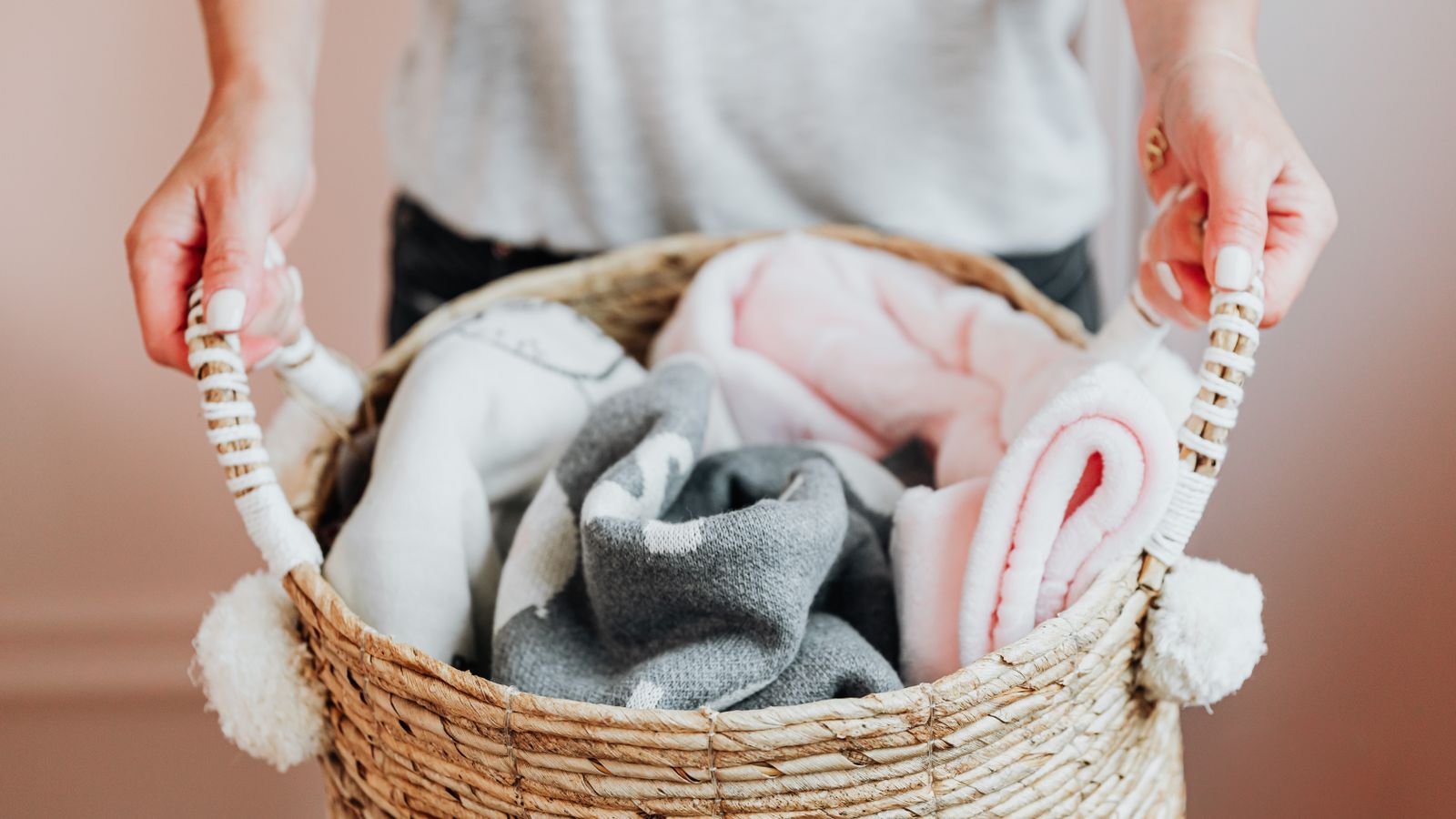 Woven storage basket filled with folded toddler blankets and a spare sheet set