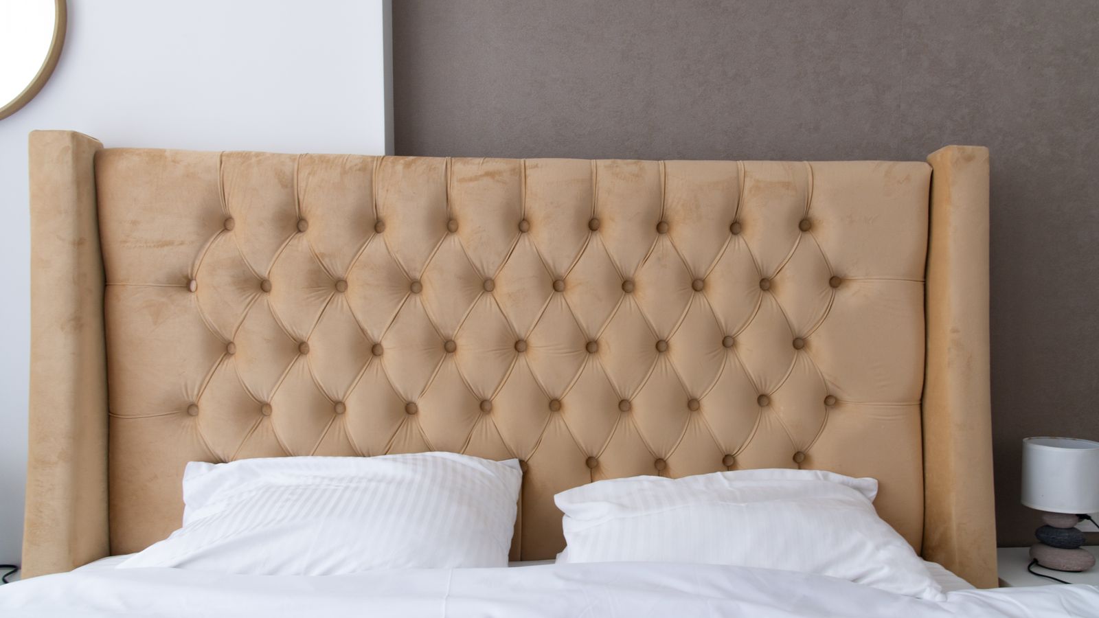 Elegant beige upholstered bed with matching pillows in a California king bedroom setup