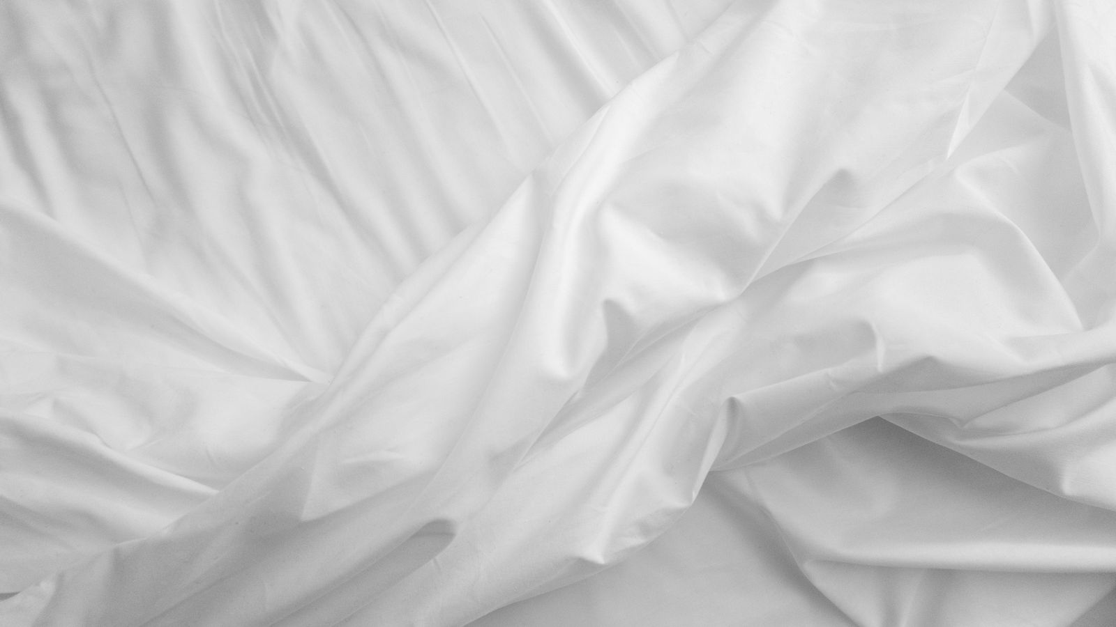 Neatly folded Tencel bed sheets stacked in a linen closet