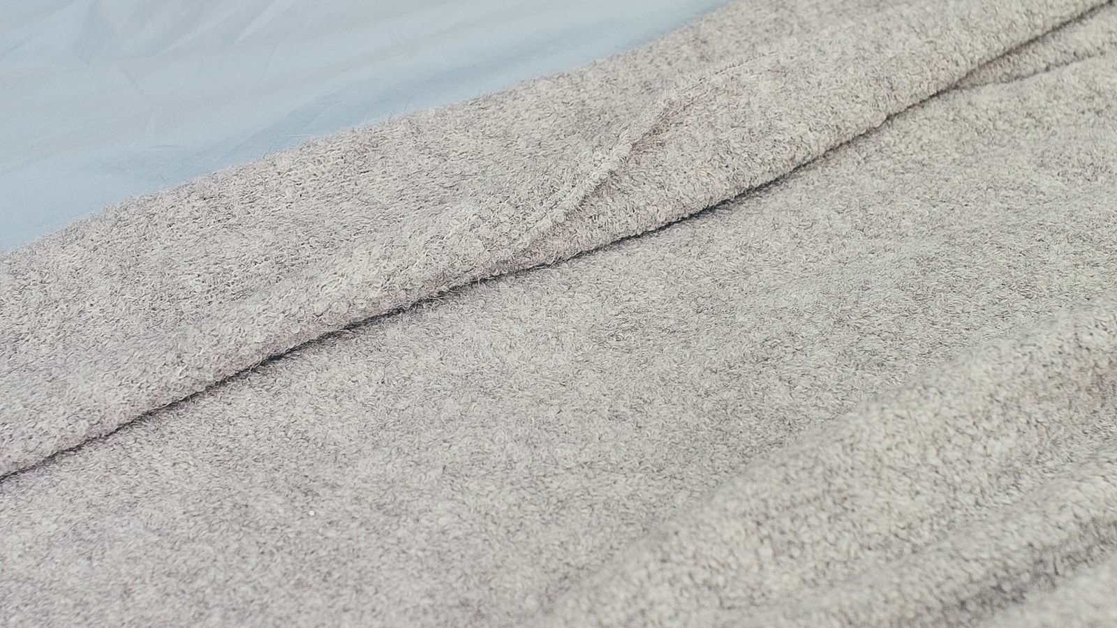 Folded waffle weave blanket layered on a made bed with smooth sheets