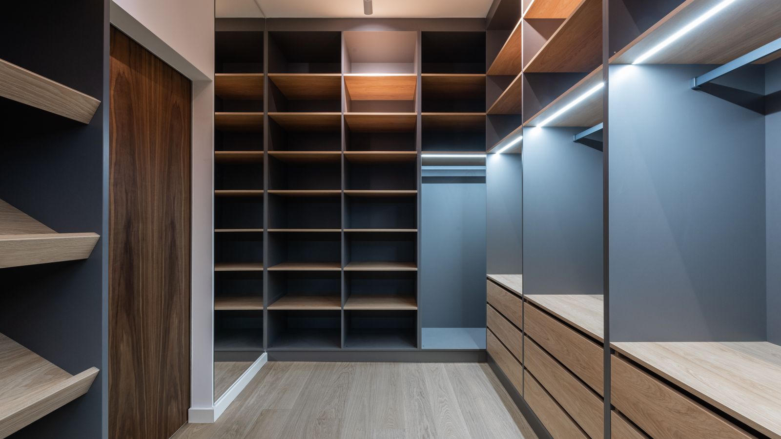 Closet shelving unit with folded clothing and labeled storage bins