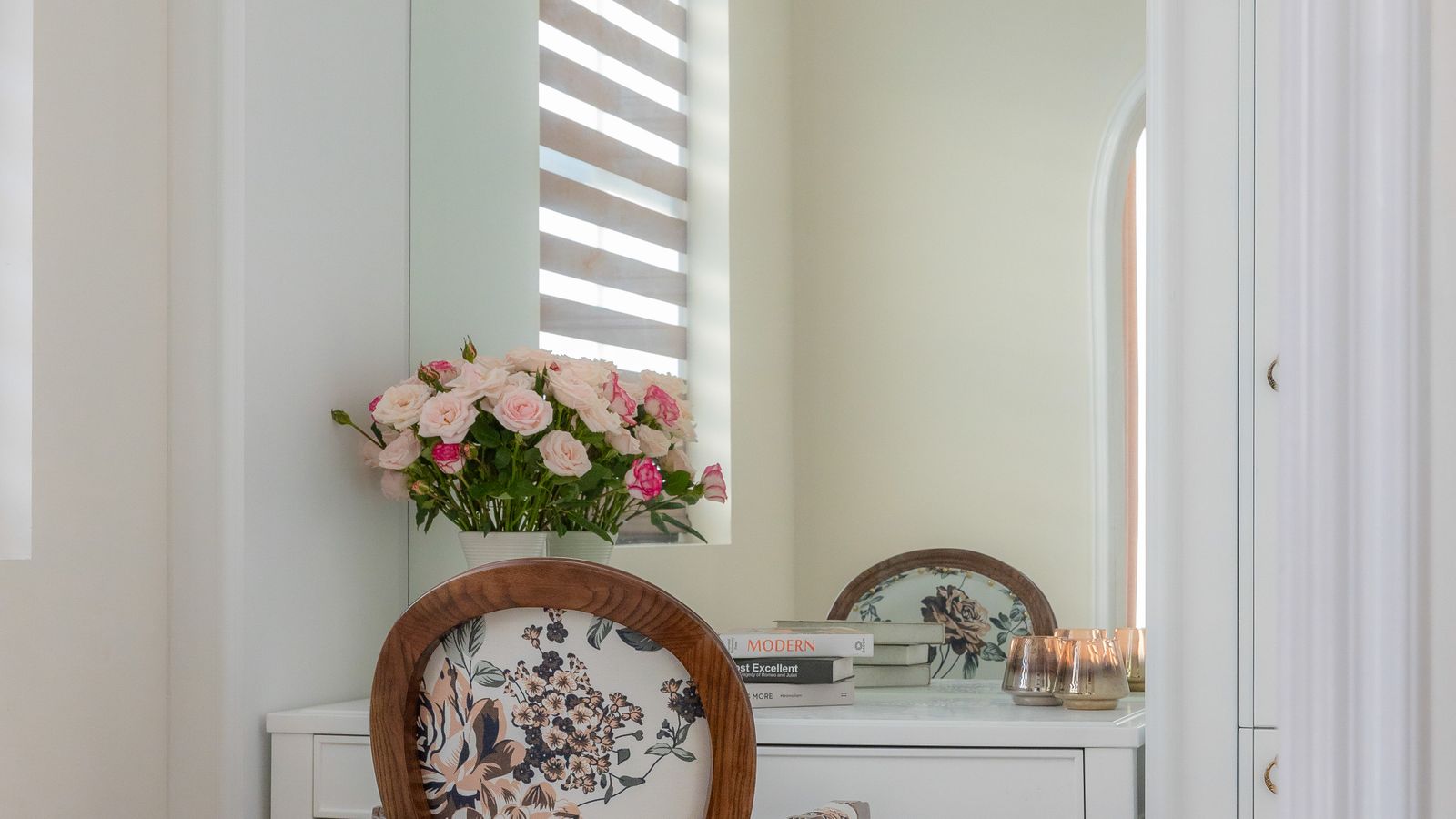 Compact vanity table and chair styled with a mirror and floral decor in a small bedroom