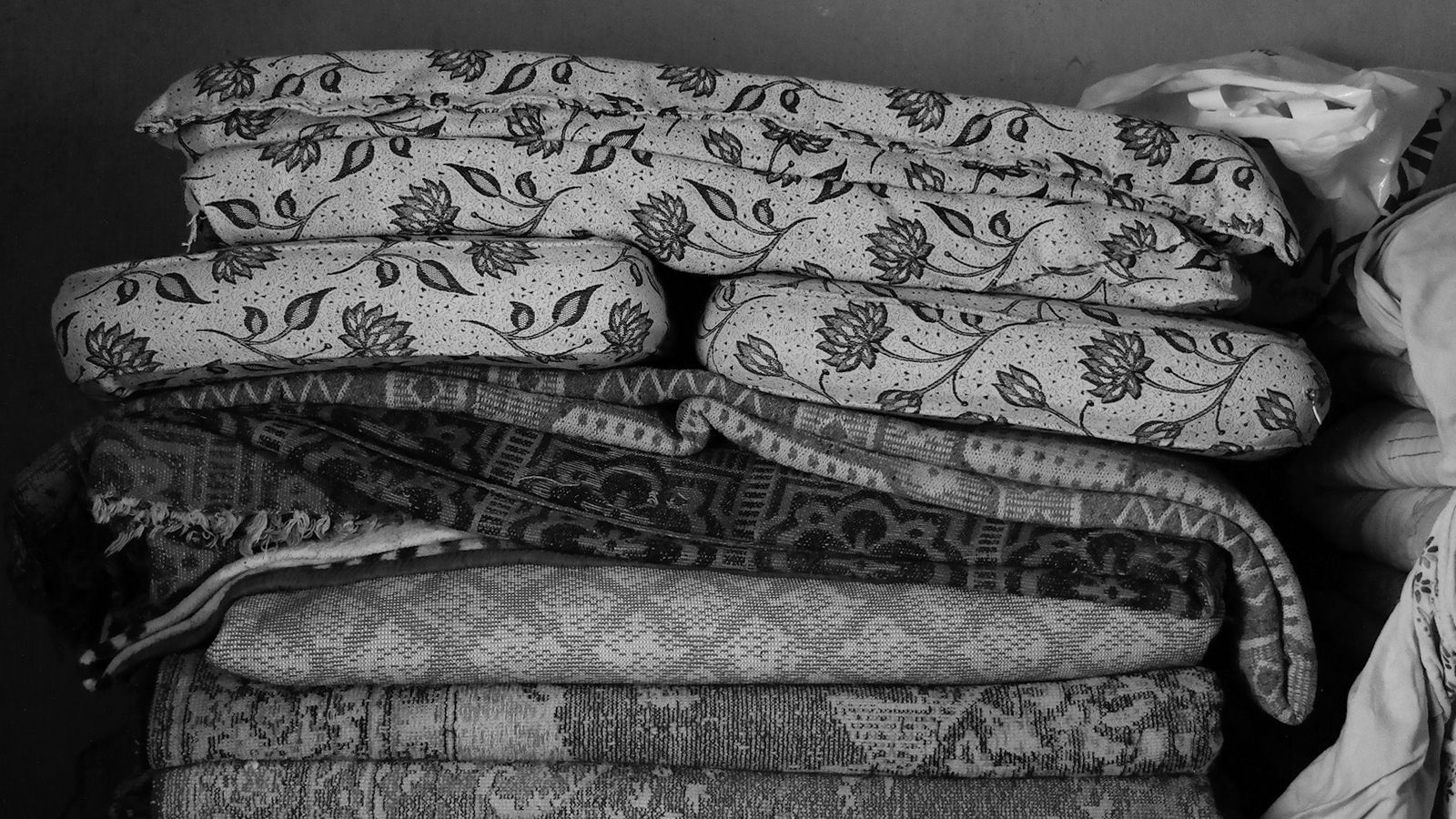 Neatly folded stack of bed linens and blankets ready for a rotation system