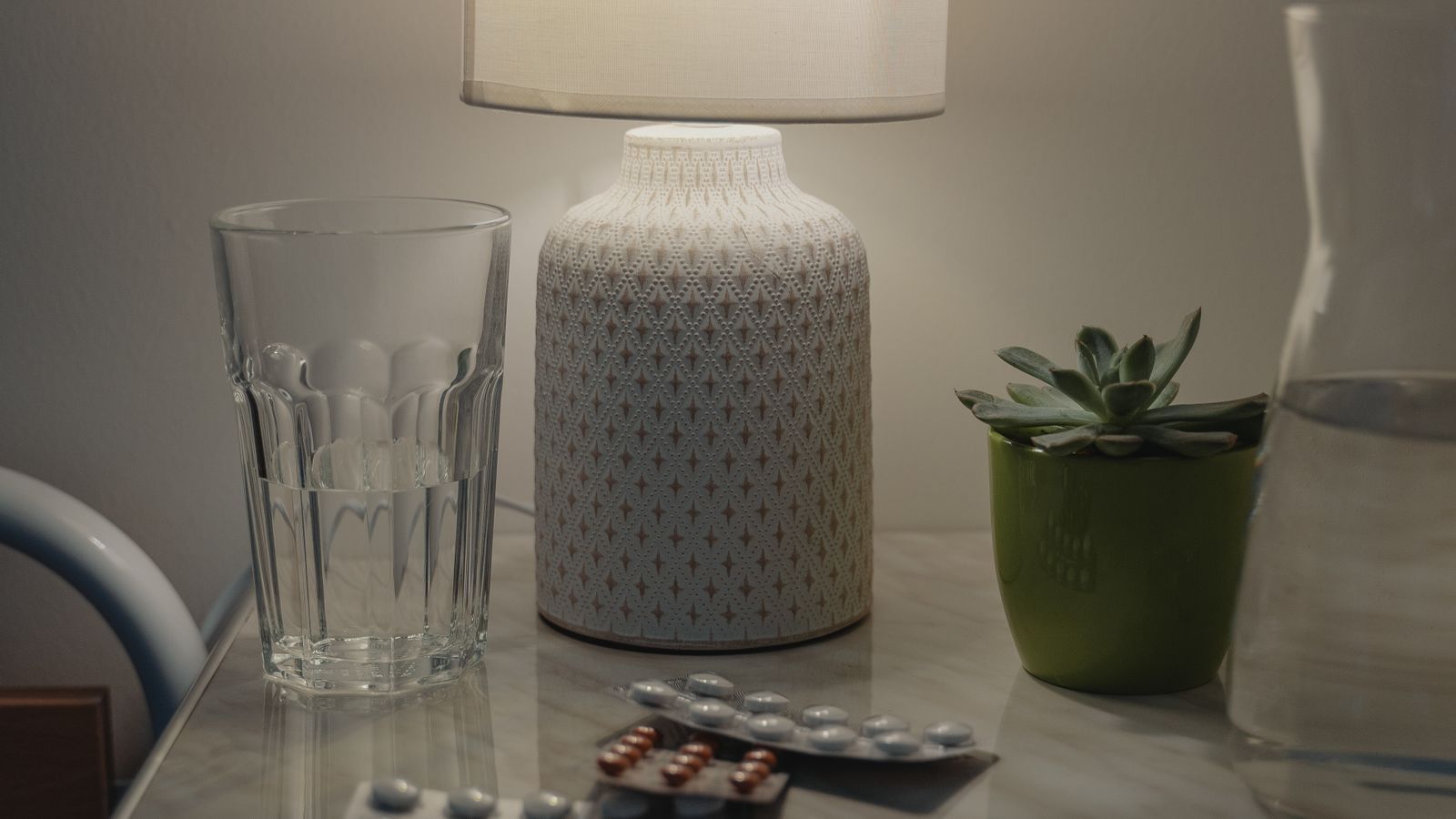 Warm bedside lamp glowing softly on a nightstand in a bedroom at night