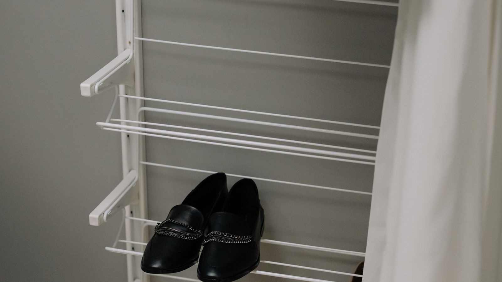 Organized closet with a wooden shoe rack holding several pairs of shoes