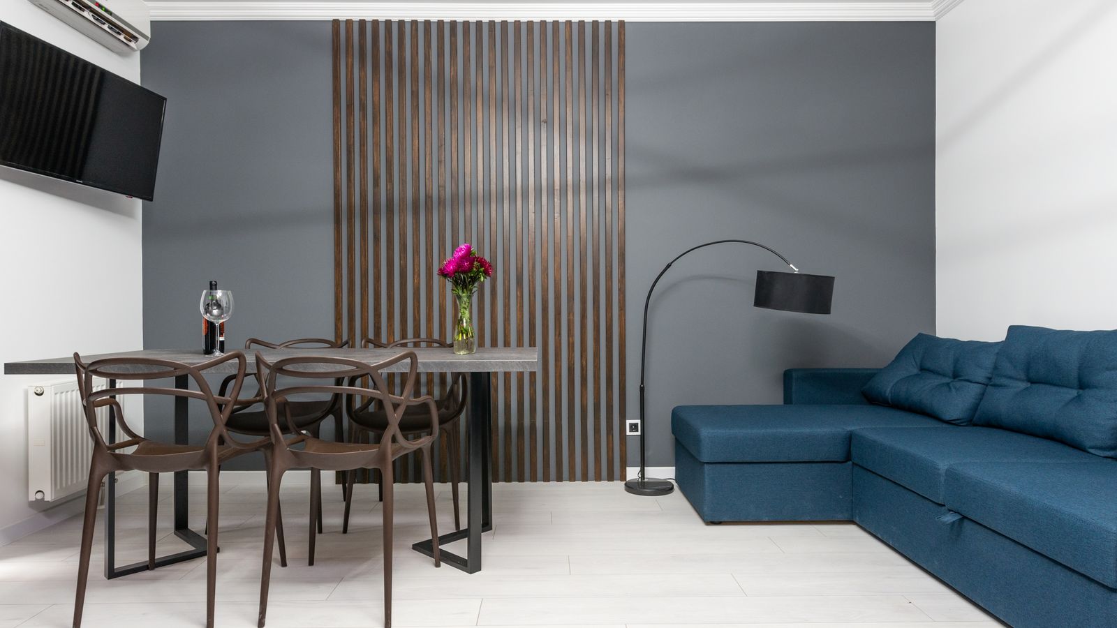 Simplified dining room wall with textured wood wall panel and arched mirror