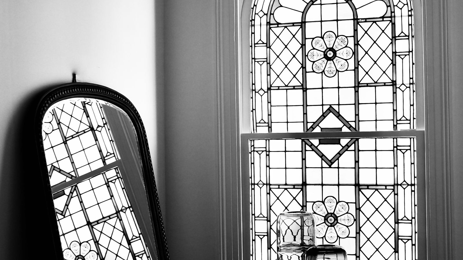 Arched mirror reflecting light above a dining console in a simplified decor scheme