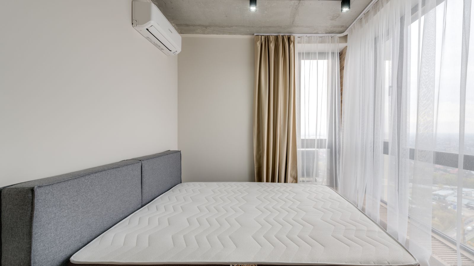 Freshly made bed with clean sheets over a protected mattress in a bright bedroom