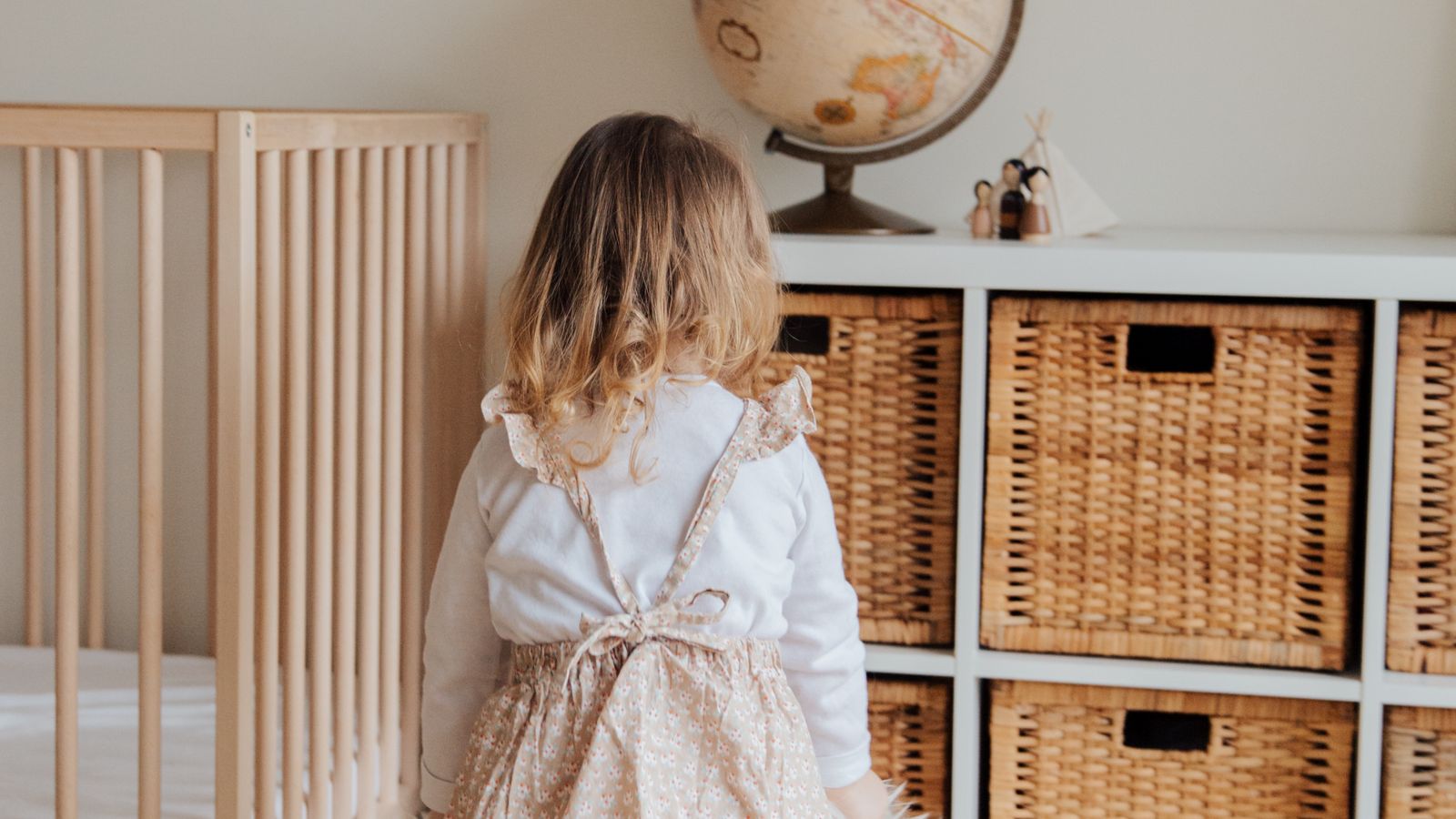 Organized nursery room with toy storage baskets and a wooden dresser