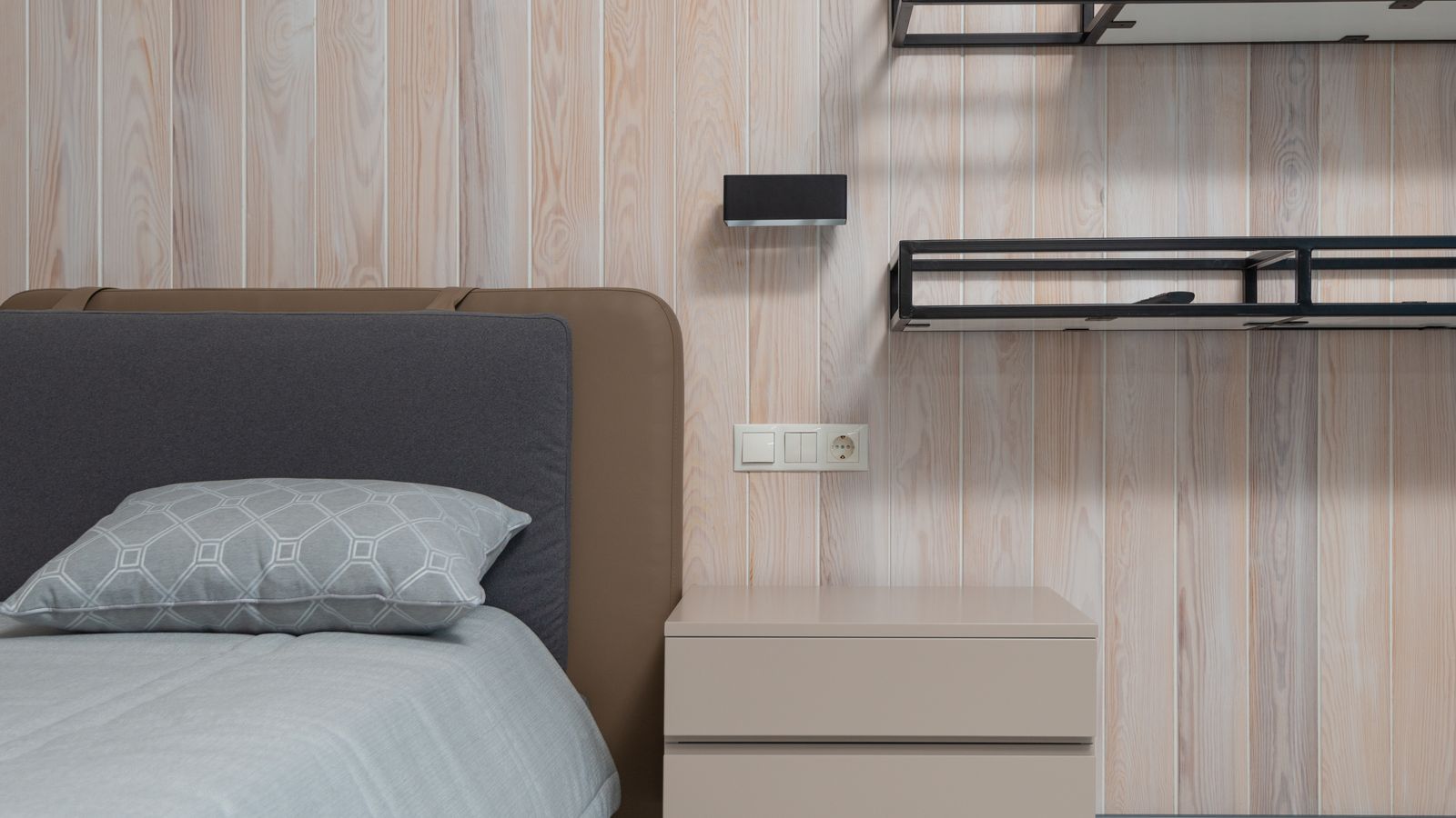 Metal headboard bracket removed from a bed frame and placed on a wooden floor before storage