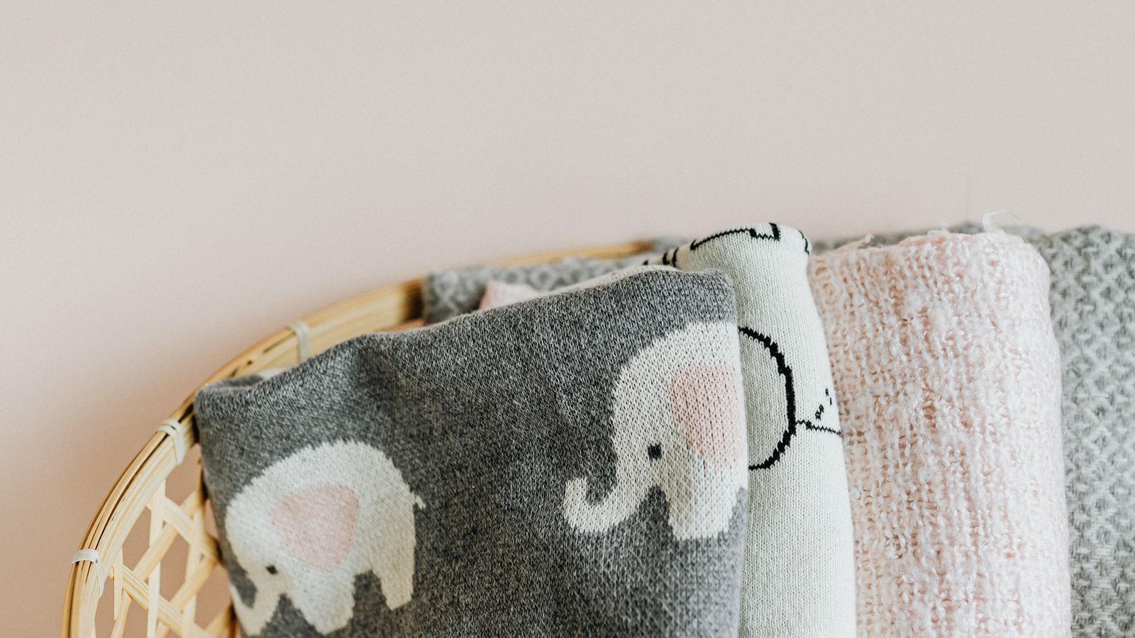 Woven blanket basket filled with folded throws beside a living room chair