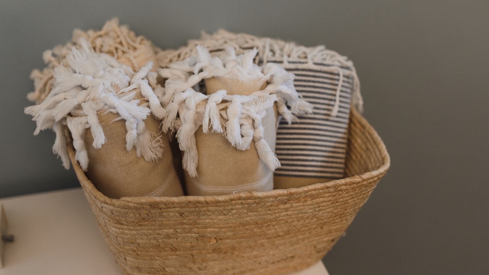 Neatly folded blankets and throws stacked inside a storage basket at home
