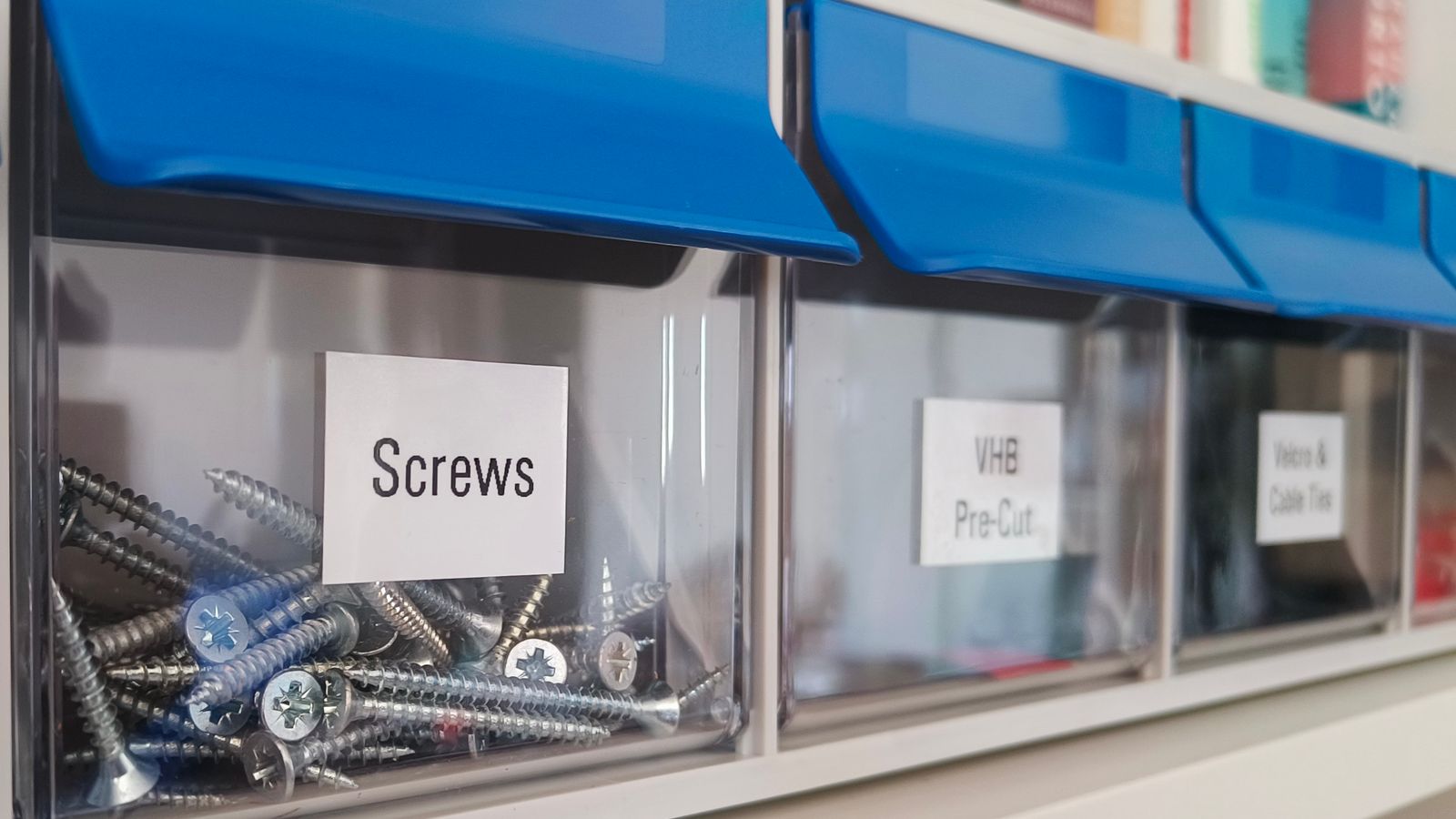 Neatly organized home workshop storage bins with labeled small parts