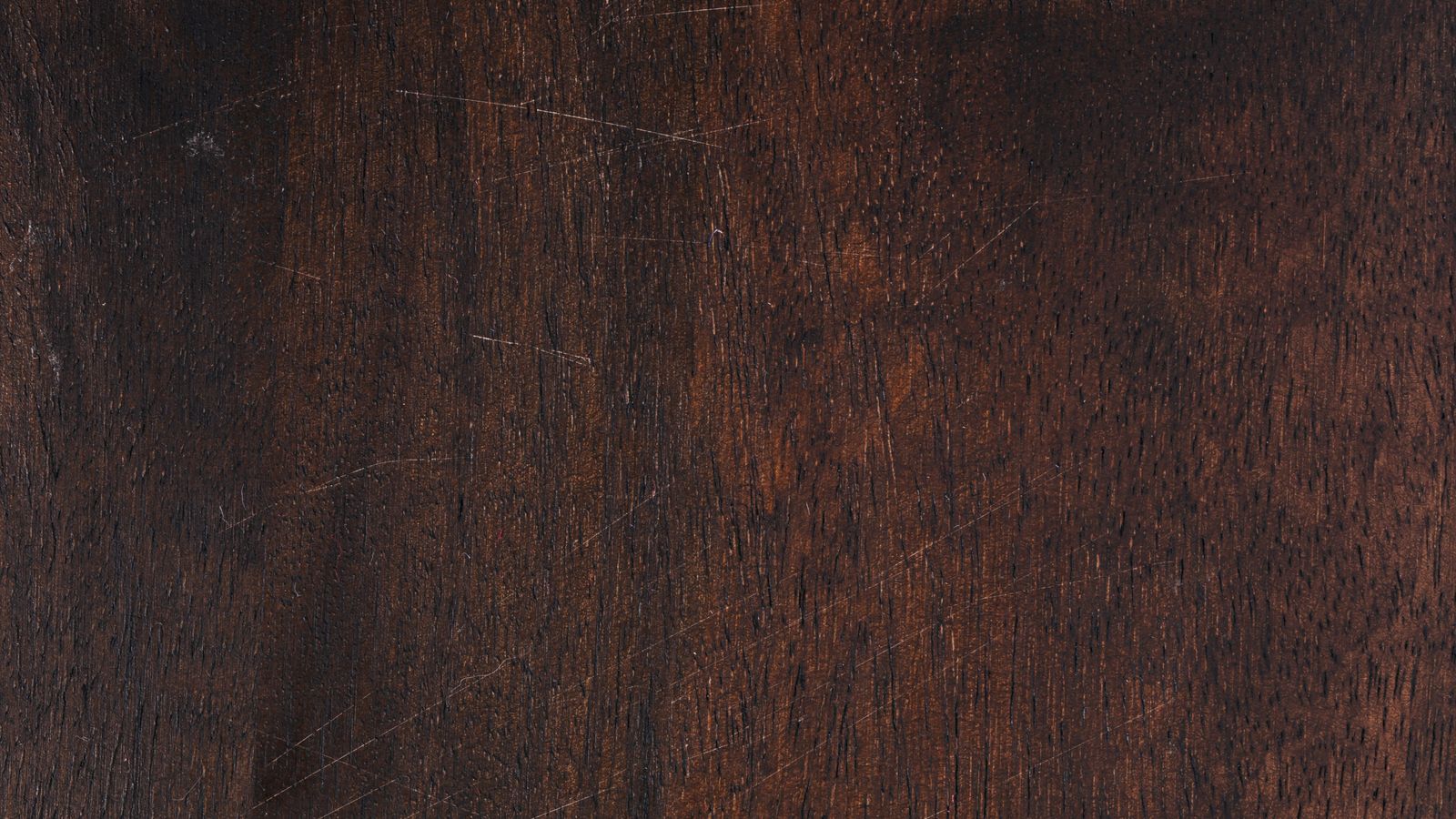 Close-up of a wood scratch repair kit with markers and filler stick beside a scratched wooden surface