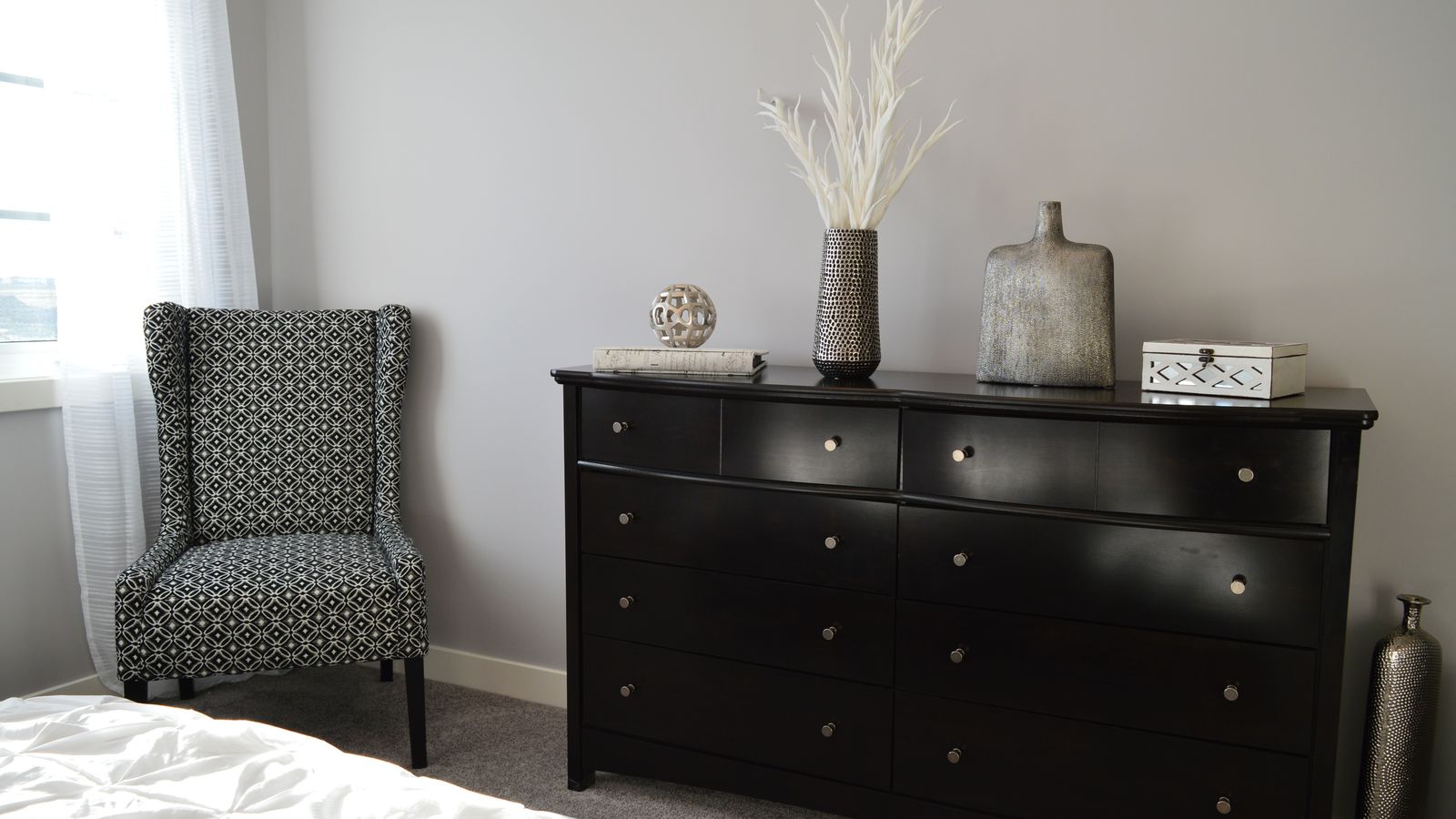 Tall narrow lingerie chest with multiple drawers in a bright bedroom corner