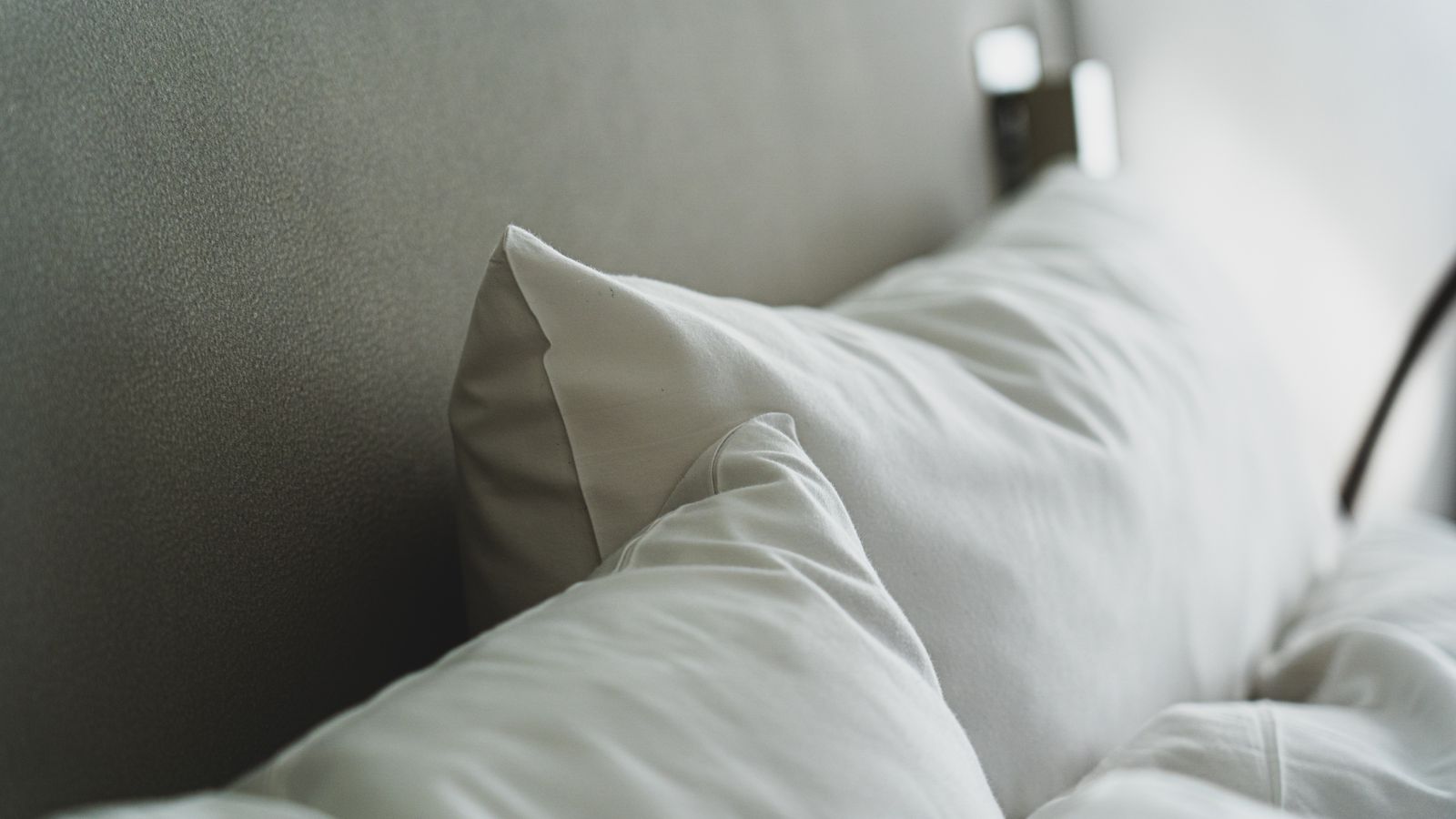 Fresh pillow being sprayed with pillow spray before placing on a made bed