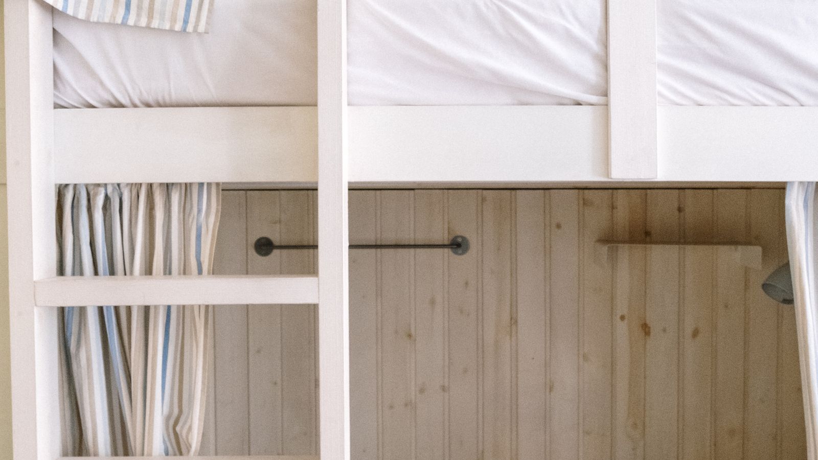 Neatly made bunk bed with fitted sheets tucked around a narrow twin mattress