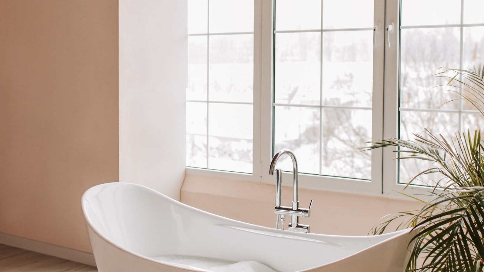 Freestanding oval soaking bathtub positioned near a window in a spacious bathroom