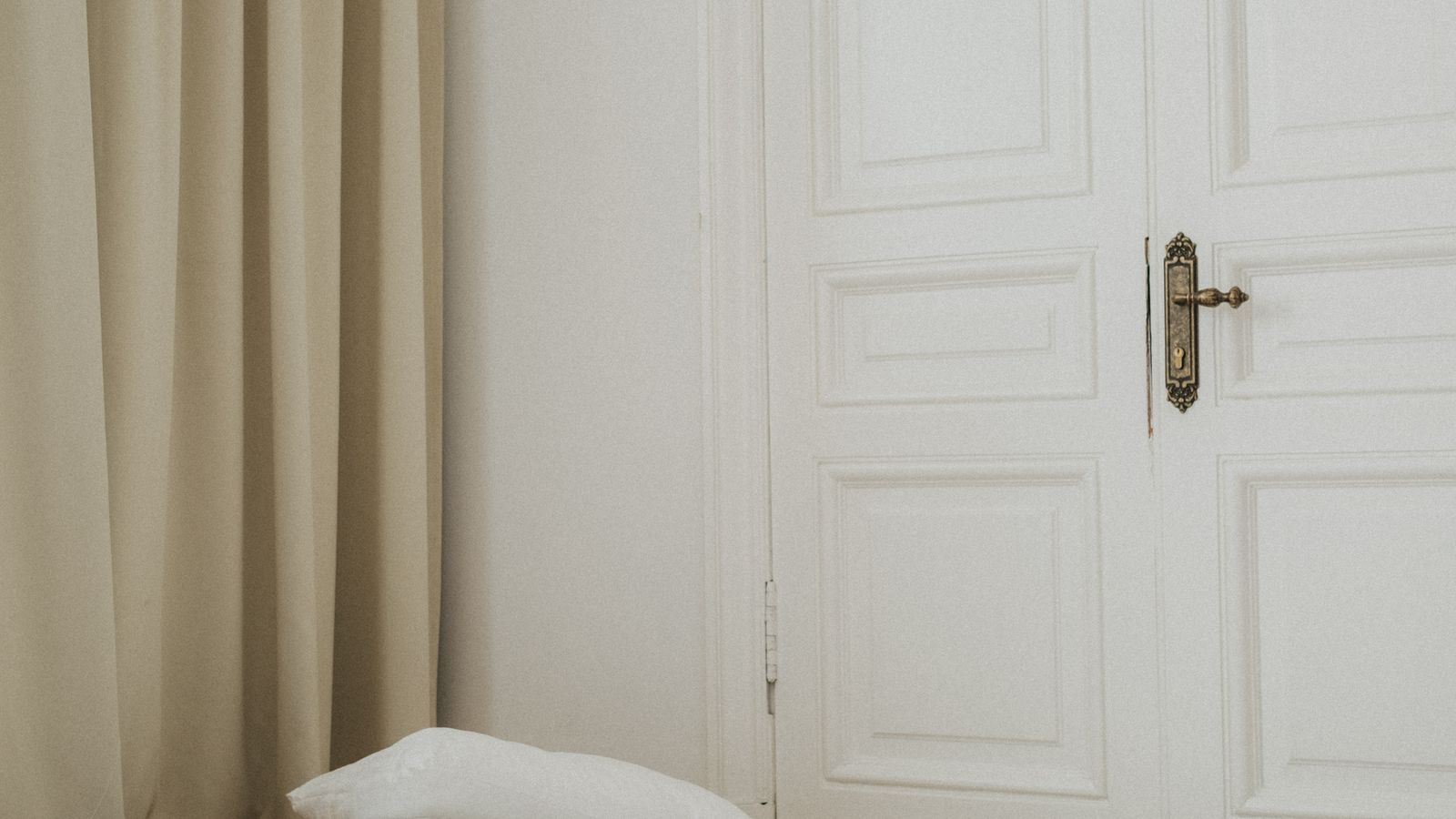 Folded futon mattress with bedding on a wooden frame in a small room