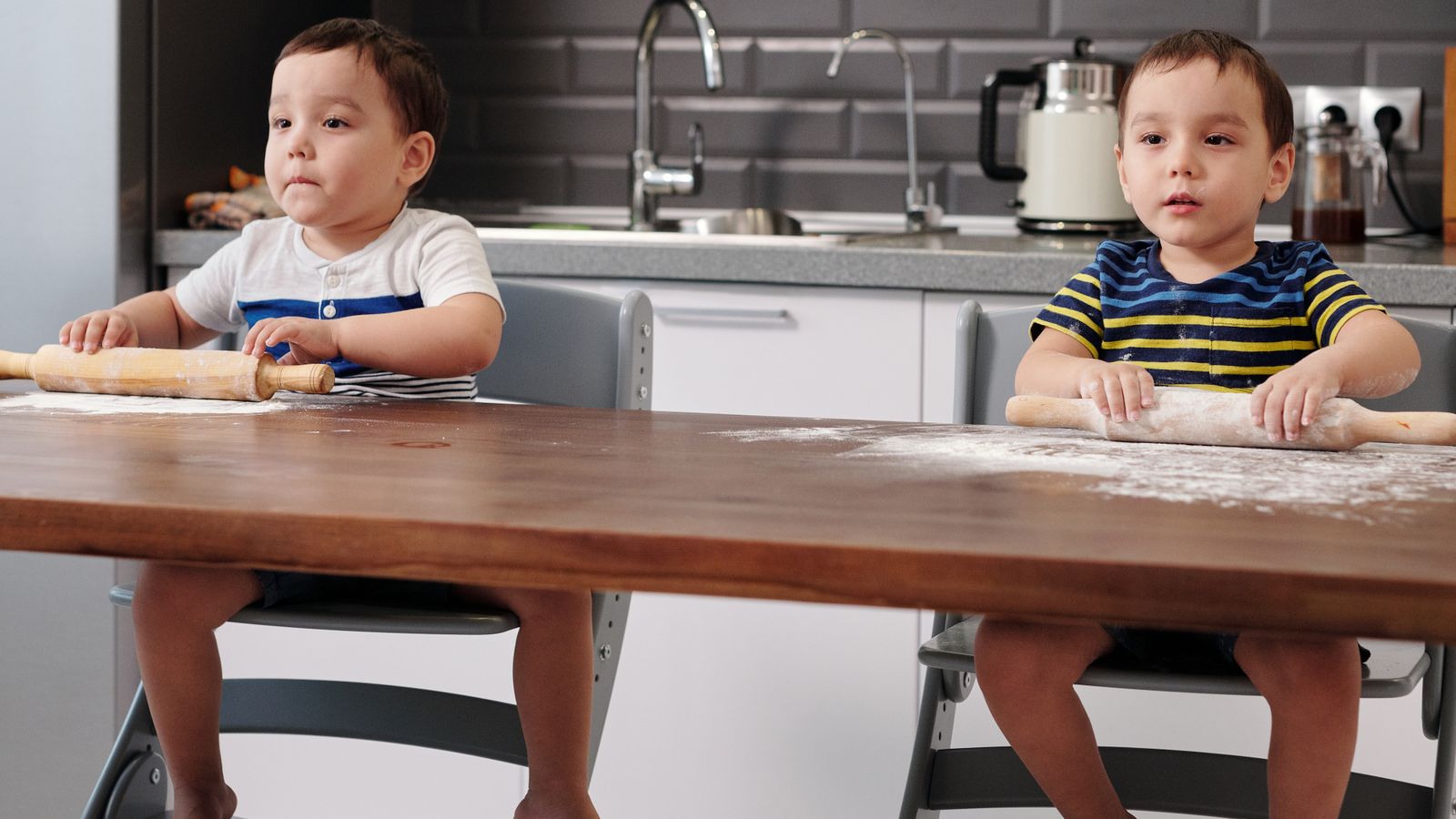 Toddler sitting in a small chair at a low activity table in a playroom